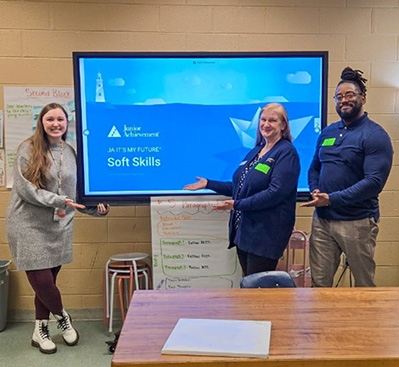 Photo of team members with a 6th grade teature in front of a screen about to give a presentation